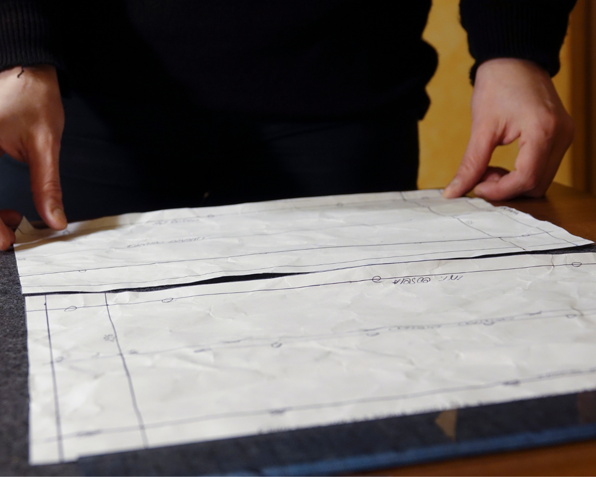 Man laying paper pattern pieces onto black fabric 